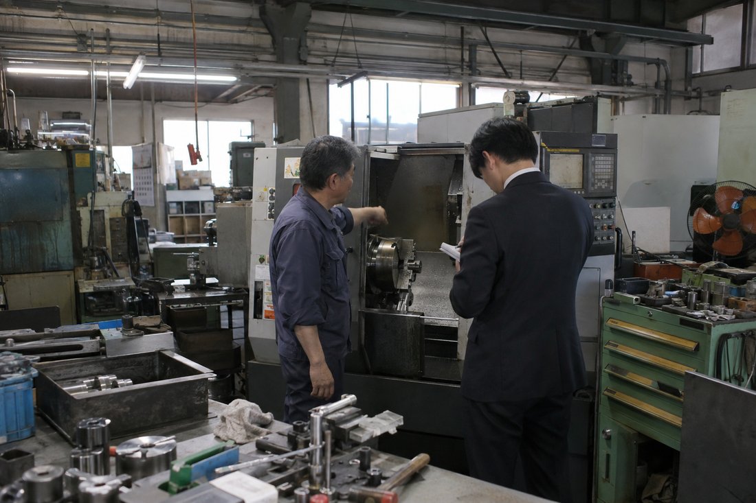 工場で社長の話を聞く担当者（イメージ）