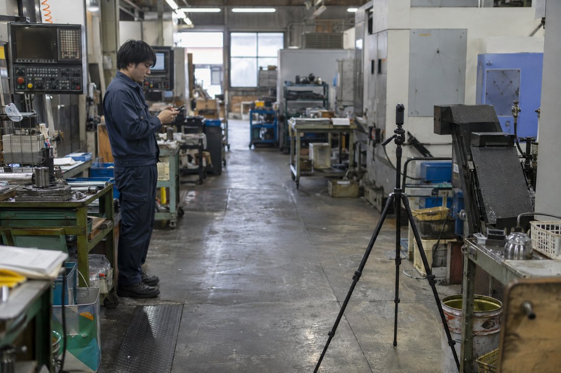 三脚に載せた360度カメラで工場内を撮影する様子